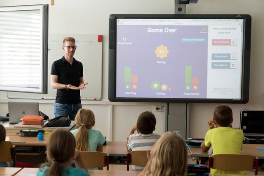 Teacher using a smart whiteboard to teach primary students in classroom.